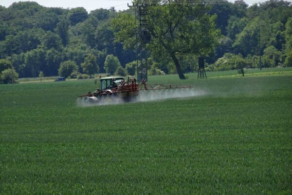 Traktor bei der Ausbringung von Pflanzenschutzmitteln auf einem Getreidefeld in der Agrarlandschaft.